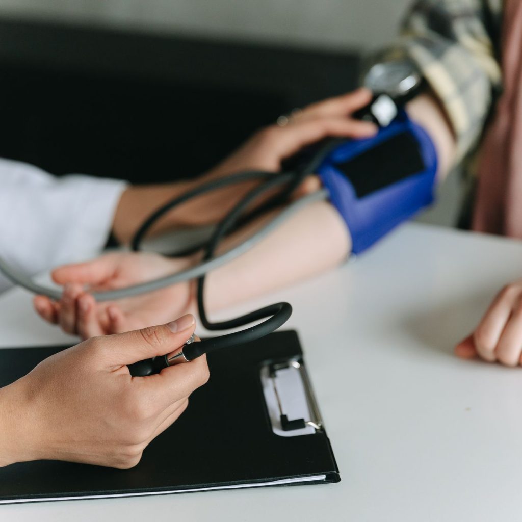 Close-up of a medical professional measuring a patient's blood pressure at a clinic. — All About Mumps Vaccination Schedule i