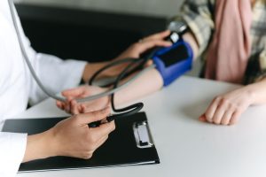 Close-up of a medical professional measuring a patient's blood pressure at a clinic. — All About Mumps Vaccination Schedule i