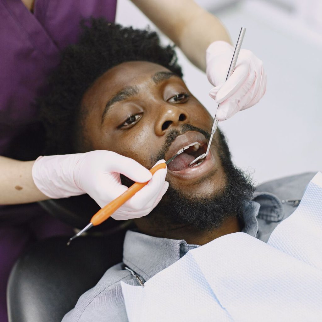 Dentist examining a man's teeth during a routine dental checkup. — Benefits of Getting Dental Implants