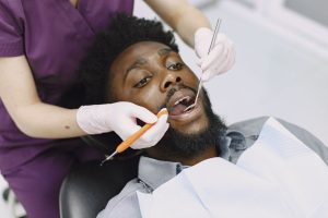 Dentist examining a man's teeth during a routine dental checkup. — Benefits of Getting Dental Implants