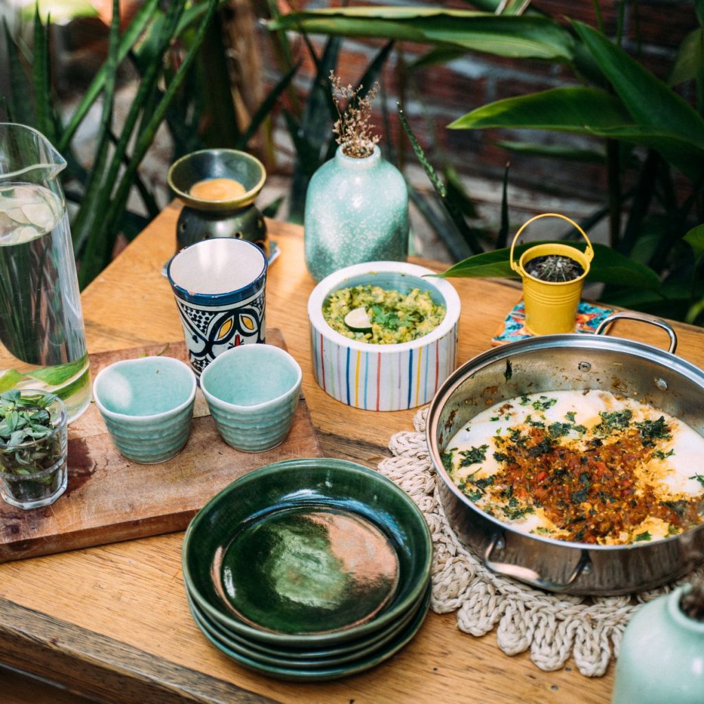 A colorful outdoor table setup with various dishes, cups, and a pitcher of water. — Best oil for Cooking for Bodybuilding