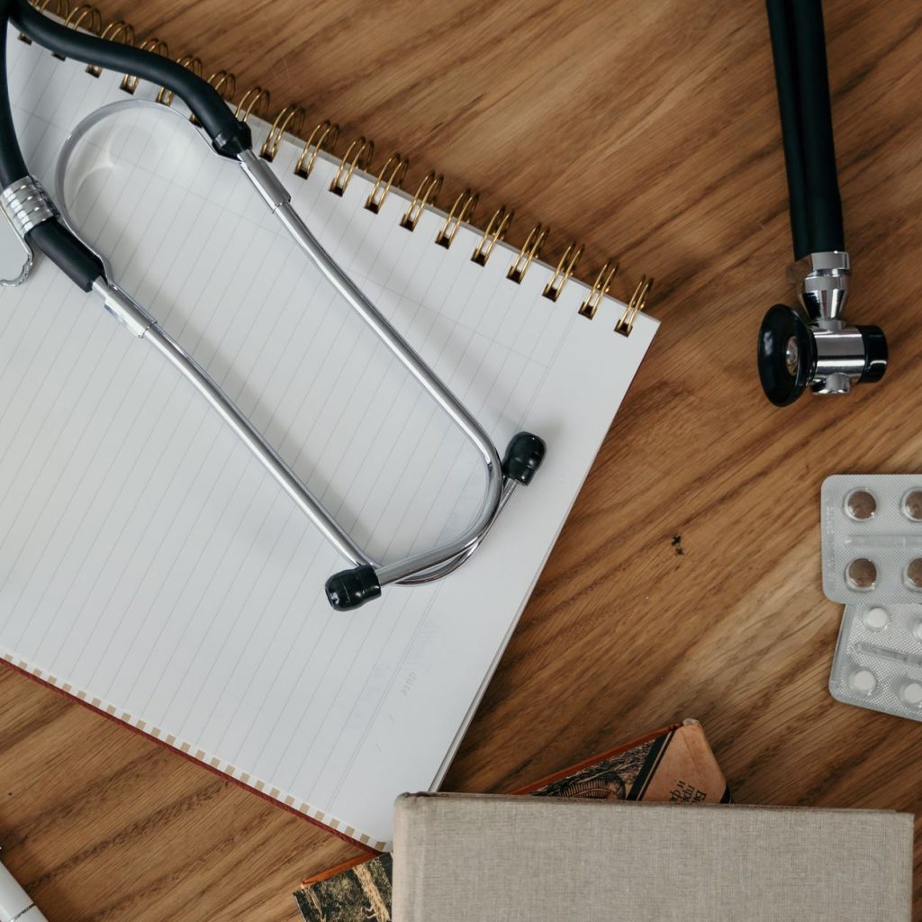 Flat lay of medical tools and supplies on a wooden desk surface. — Bringing Quality Health Services to You