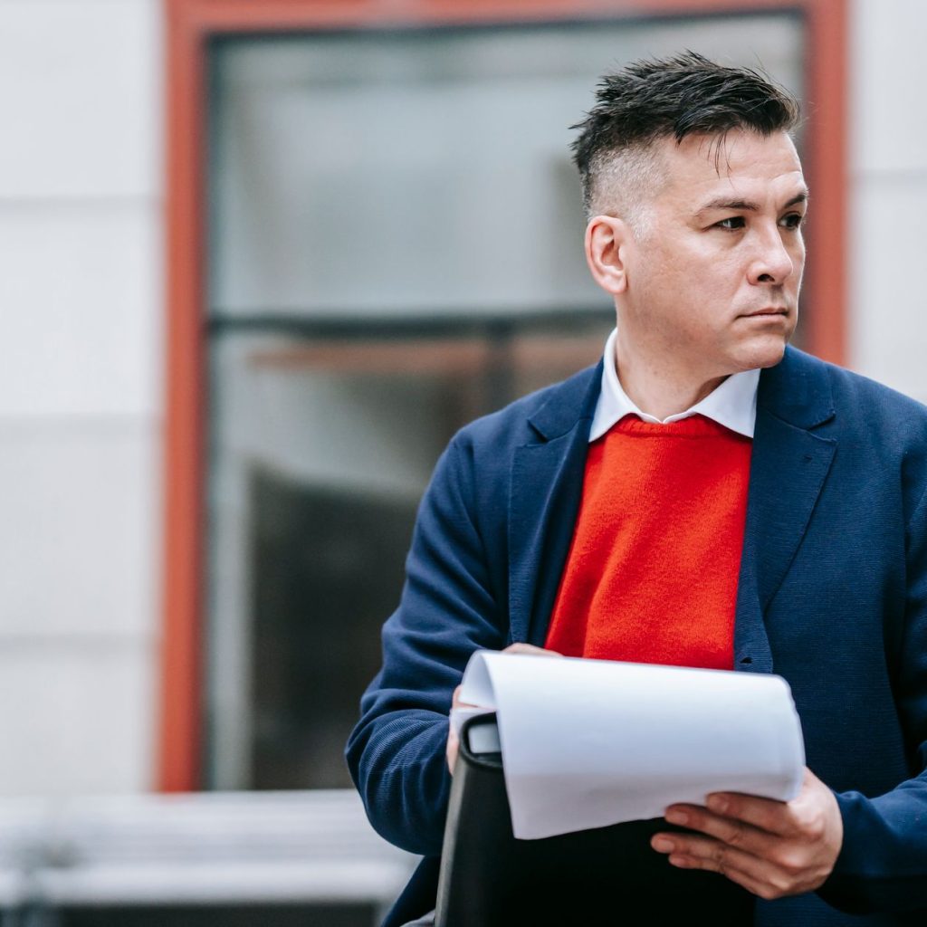 A serious man holding papers, dressed professionally in an urban environment. — Comparing Humana's 2024 Medicare Advantage Pl
