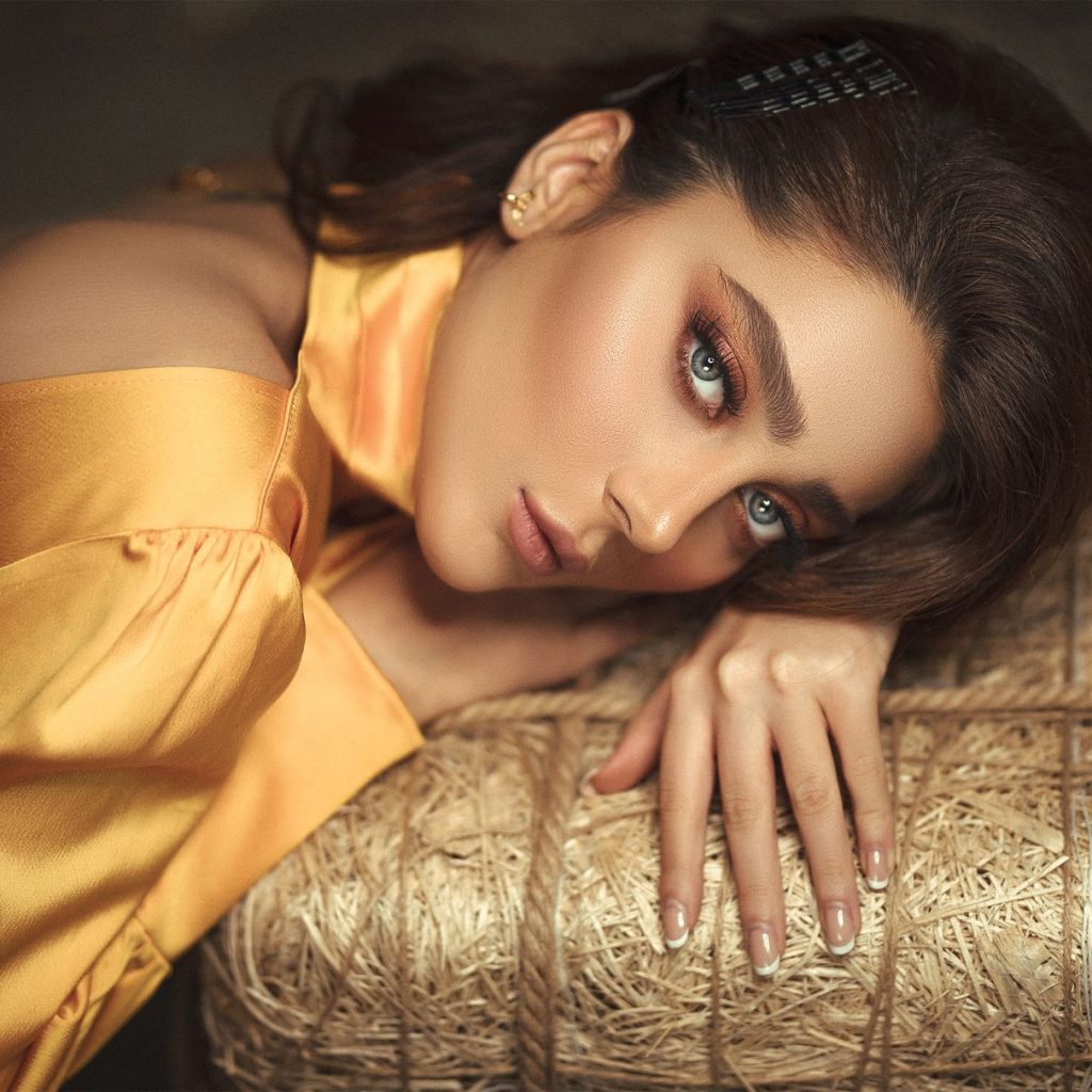 Portrait of a woman in elegant golden silk attire, lying gracefully on textured surface. — Details Add Style and Function to