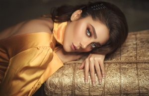 Portrait of a woman in elegant golden silk attire, lying gracefully on textured surface. — Details Add Style and Function to