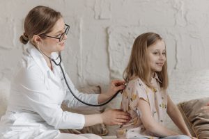 A doctor uses a stethoscope during a check-up with a young girl in a medical setting. — Enhancing Health Naturally: The Power