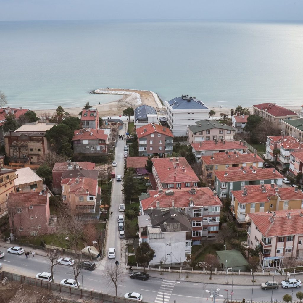 Aerial shot of a picturesque coastal town with red rooftops and a serene ocean view. — Experience the Power of Breast Augment