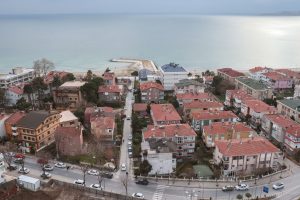Aerial shot of a picturesque coastal town with red rooftops and a serene ocean view. — Experience the Power of Breast Augment