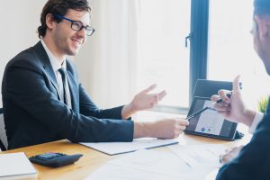 Two businessmen in formal attire discussing a business report in an office setting with a tablet. — Exploring Plastic Surgery