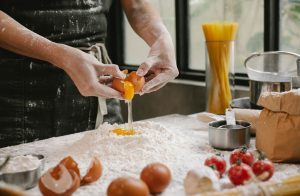 Crop anonymous person adding egg in flour while cooking pastry for recipe with cherry tomatoes and spaghetti — Food Allergies