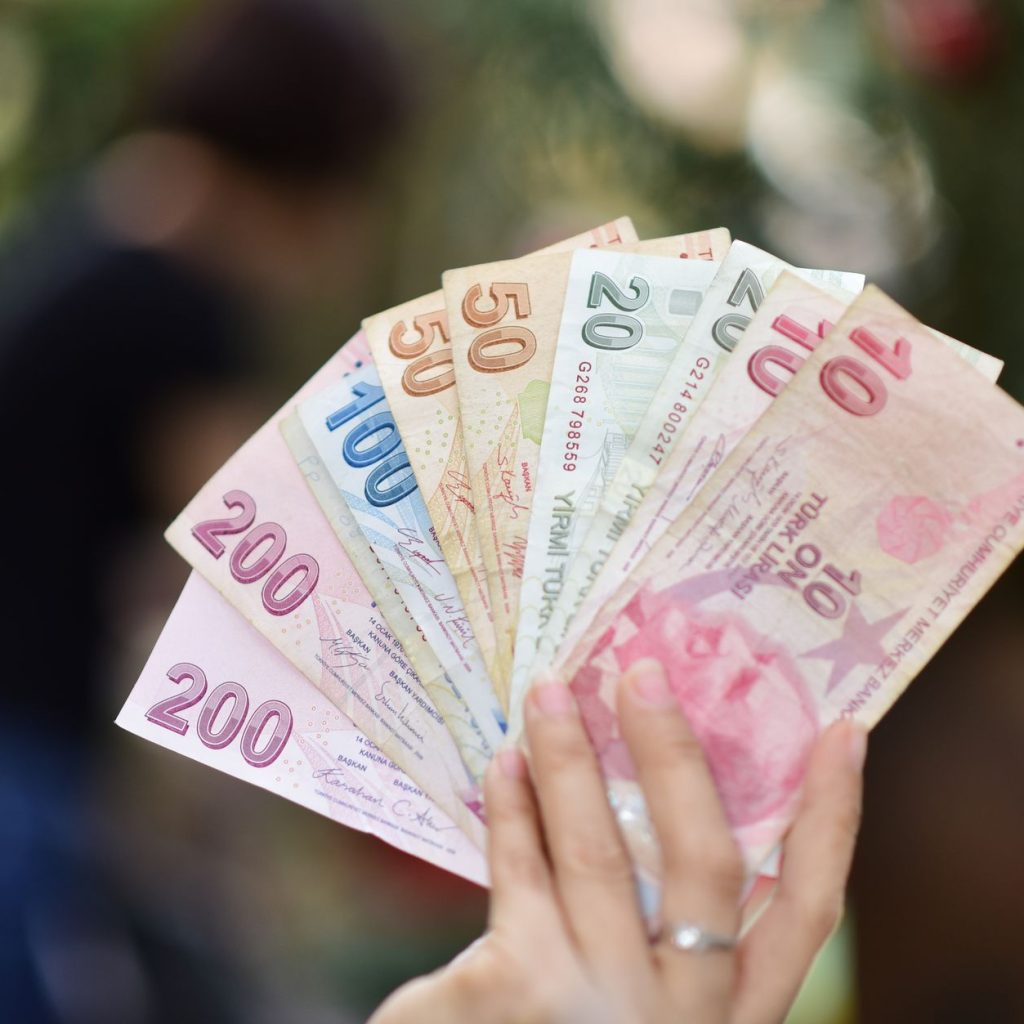 A hand holding various Turkish Lira banknotes with a blurred outdoor background. — Generating Quality Leads with White Label