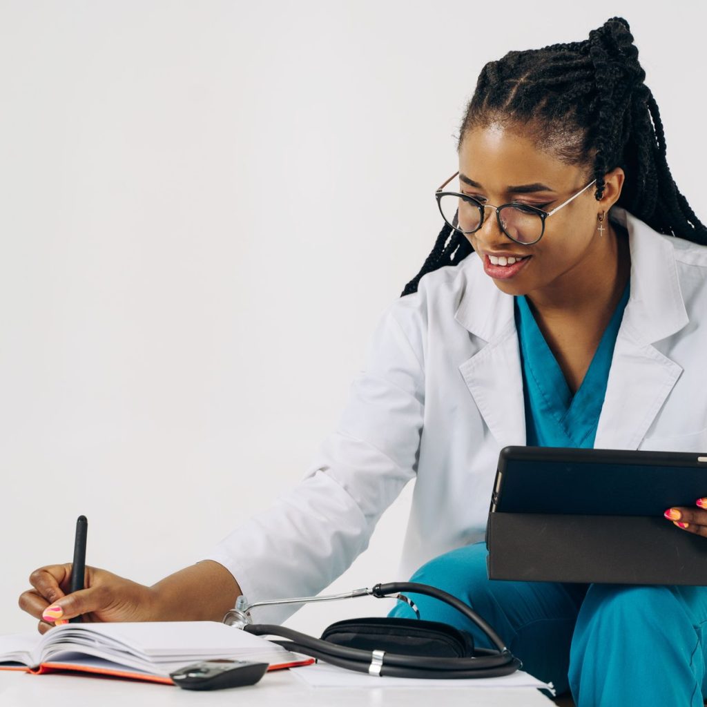 Smiling female doctor in scrubs using tablet and taking notes in a healthcare setting. — Here are some of the common queries