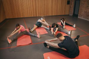 Adults in a yoga studio stretch on mats, promoting fitness and flexibility. — Home Fitness Exercise - Keeping Off Those Extra