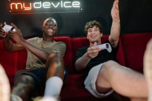 Two friends having fun and playing video games on a couch indoors. — How can I tell if an online casino is legit?
