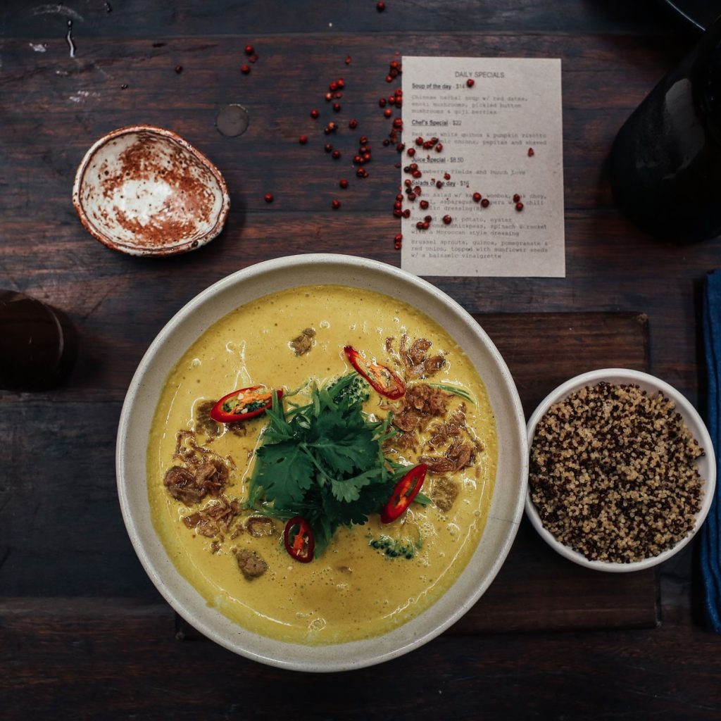 Delicious spicy curry soup with quinoa and fresh herbs served on a rustic table. — How Many Cheat Meals Can I Have A Week?