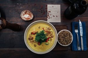 Delicious spicy curry soup with quinoa and fresh herbs served on a rustic table. — How Many Cheat Meals Can I Have A Week?