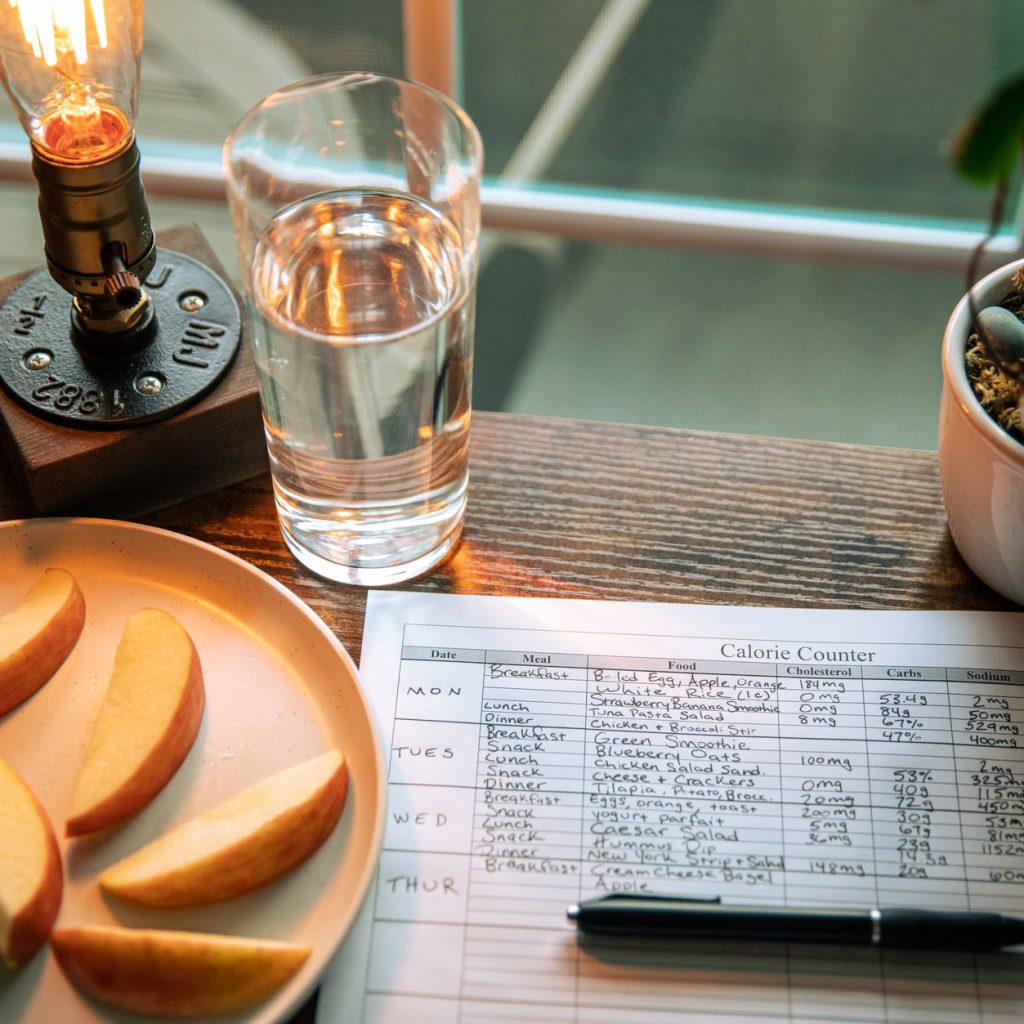 A cozy desk setup with apple slices, calorie counter, and water glass in warm lighting. — How To Chose A Diet That Really Wor