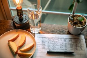 A cozy desk setup with apple slices, calorie counter, and water glass in warm lighting. — How To Chose A Diet That Really Wor