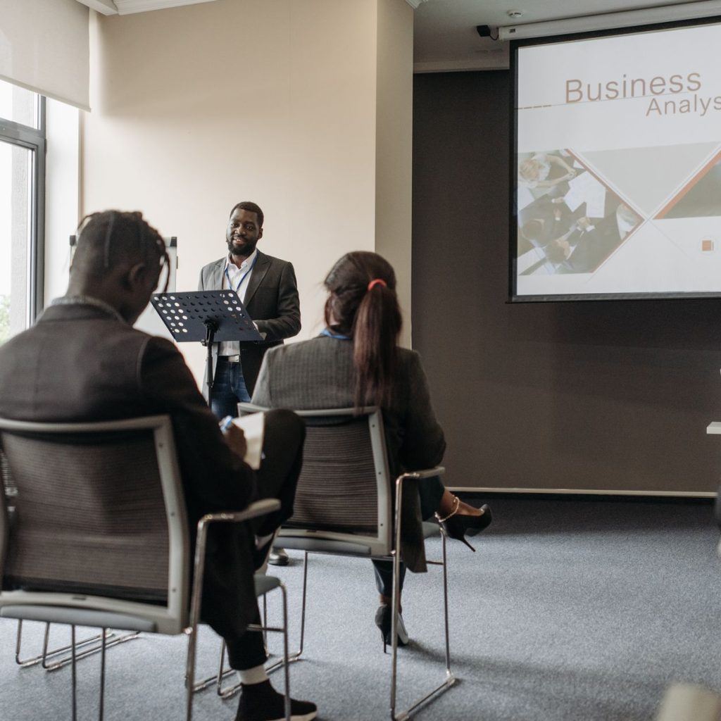 A business professional delivering a presentation in a conference room with diverse attendees. — Innovations in Drug Impairme