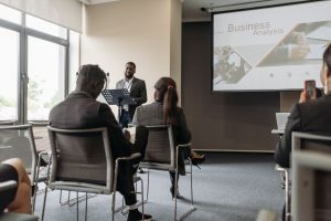 A business professional delivering a presentation in a conference room with diverse attendees. — Innovations in Drug Impairme