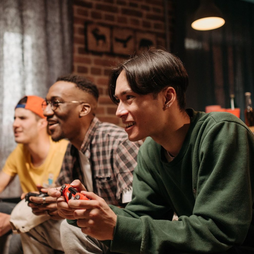 Diverse group of young adults enjoying video games together indoors, creating a fun and social atmosphere. — Make a Fortune w