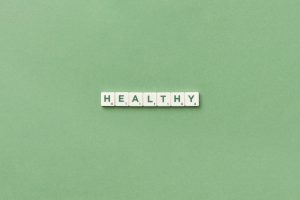 Scrabble tiles spelling the word 'healthy' on a light green background, top view. — Medical Cannabis and the Blood Donation Q