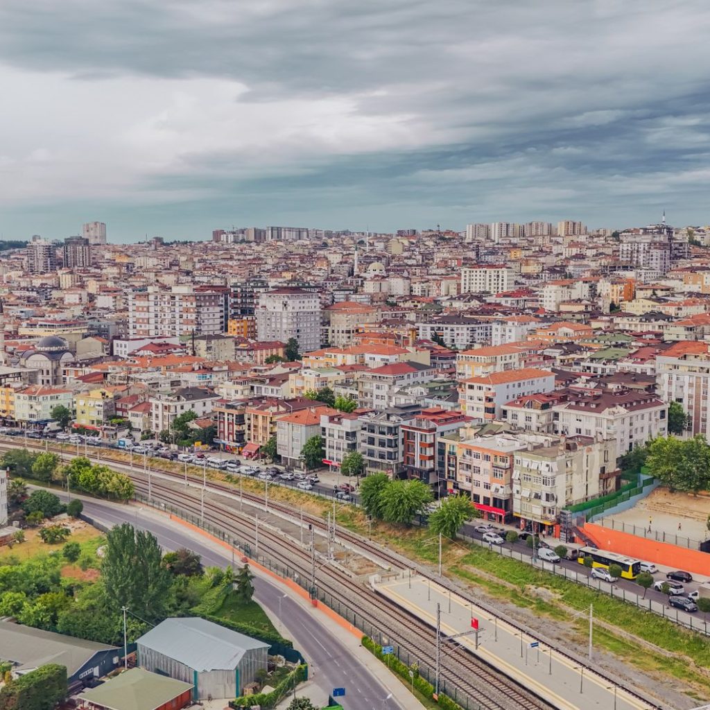 Aerial view of dense urban architecture with roads and greenery under cloudy skies. — Resume Build To Present Yourself