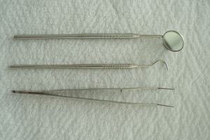 A set of dental instruments laid out on a white textured background, perfect for medical contexts. — Reviews about dentists i