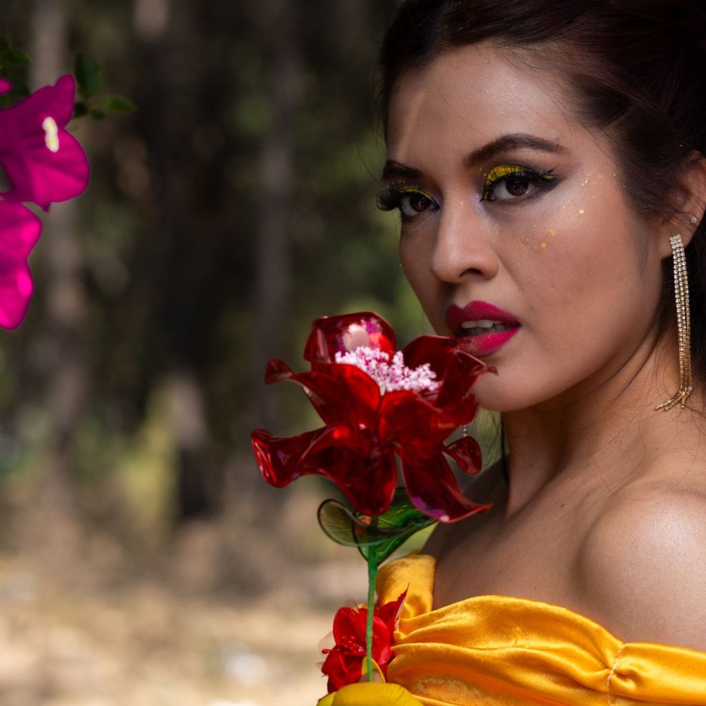Woman in princess costume holding a flower, surrounded by vibrant blooms outdoors. — Smartest Options with the Best Shampoos