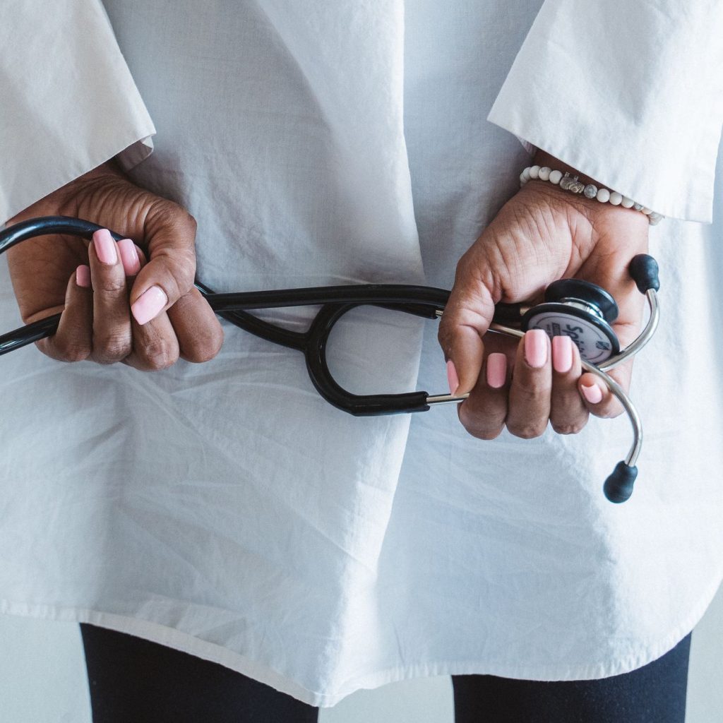 A medical professional holding a stethoscope in a clinical setting. — Stand Up And Glo!