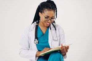 Smiling female doctor with stethoscope reading medical documents. — Suffering from piles? Get the best consultation for Piles