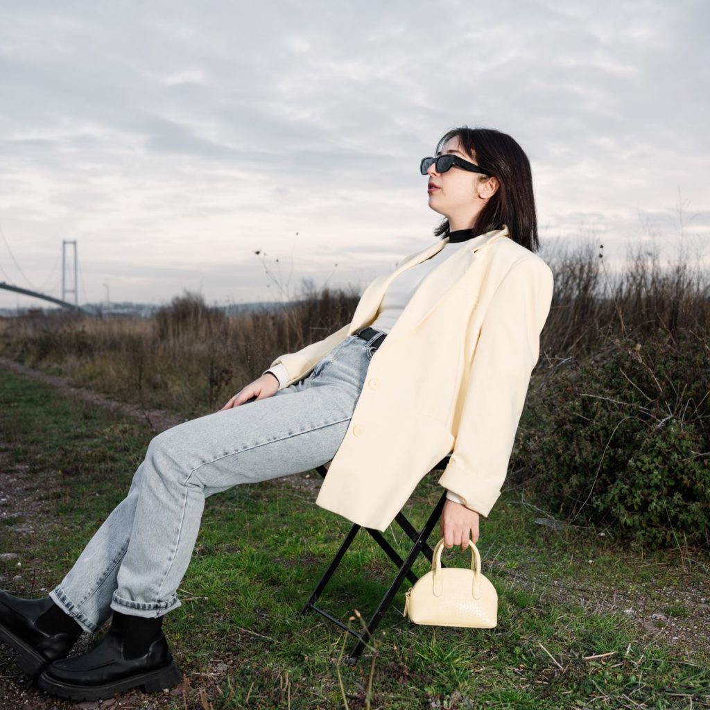 A stylish woman in sunglasses relaxes on a chair by a bridge in nature. — The Canada Startup Visa Program: A Pathway to Globa