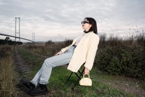 A stylish woman in sunglasses relaxes on a chair by a bridge in nature. — The Canada Startup Visa Program: A Pathway to Globa