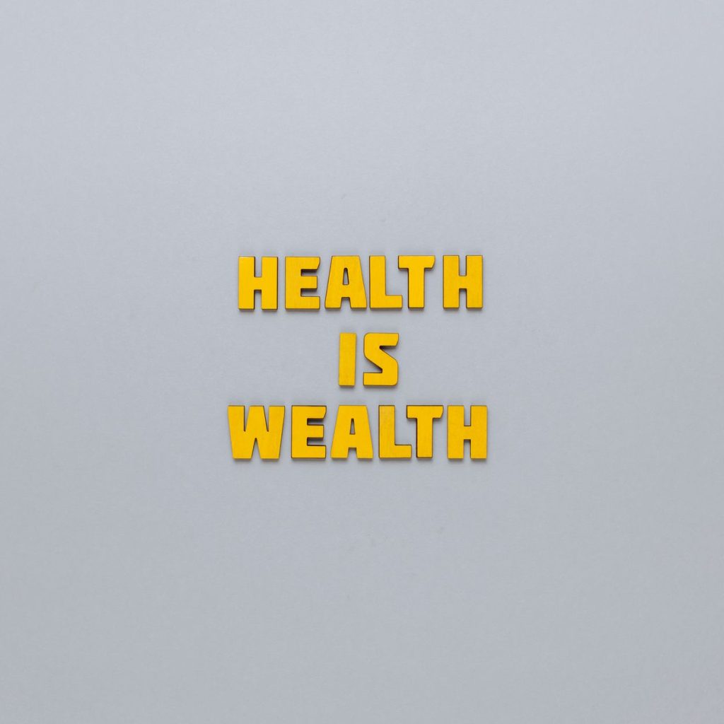 Inspirational phrase 'Health is Wealth' in bold yellow letters on a neutral gray background. — The hair condition is affected