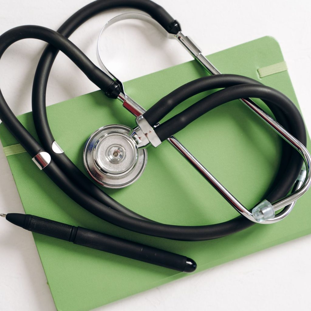 Top view of a stethoscope and pen on a green notepad, ideal for medical and educational themes. — University Hospital Settles
