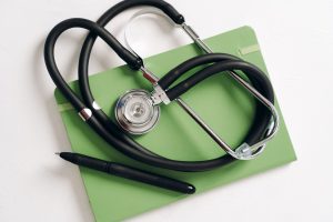 Top view of a stethoscope and pen on a green notepad, ideal for medical and educational themes. — University Hospital Settles