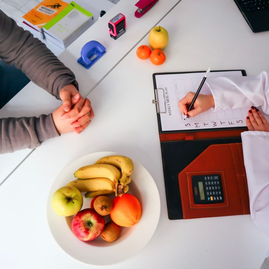 Top view of a dietitian planning a healthy diet with fresh fruits on the table, focusing on health and nutrition. — What Are