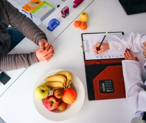 Top view of a dietitian planning a healthy diet with fresh fruits on the table, focusing on health and nutrition. — What Are