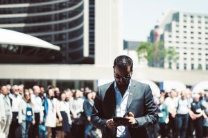 Focused businessman using tablet in a bustling crowd in Toronto's busy urban setting. — What to anticipate from Women's Good