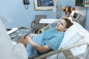 Caucasian woman in hospital bed receiving care from healthcare professional. — Where To Find Pregnancy Help